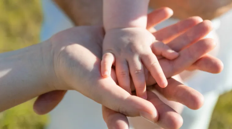 Une main d'enfant se tient dans la main de deux adultes